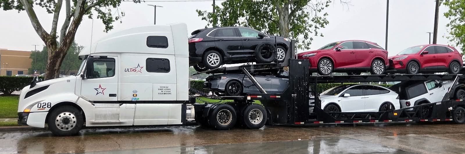 ULTAS truck 028 loaded with SUVs on a rainy day